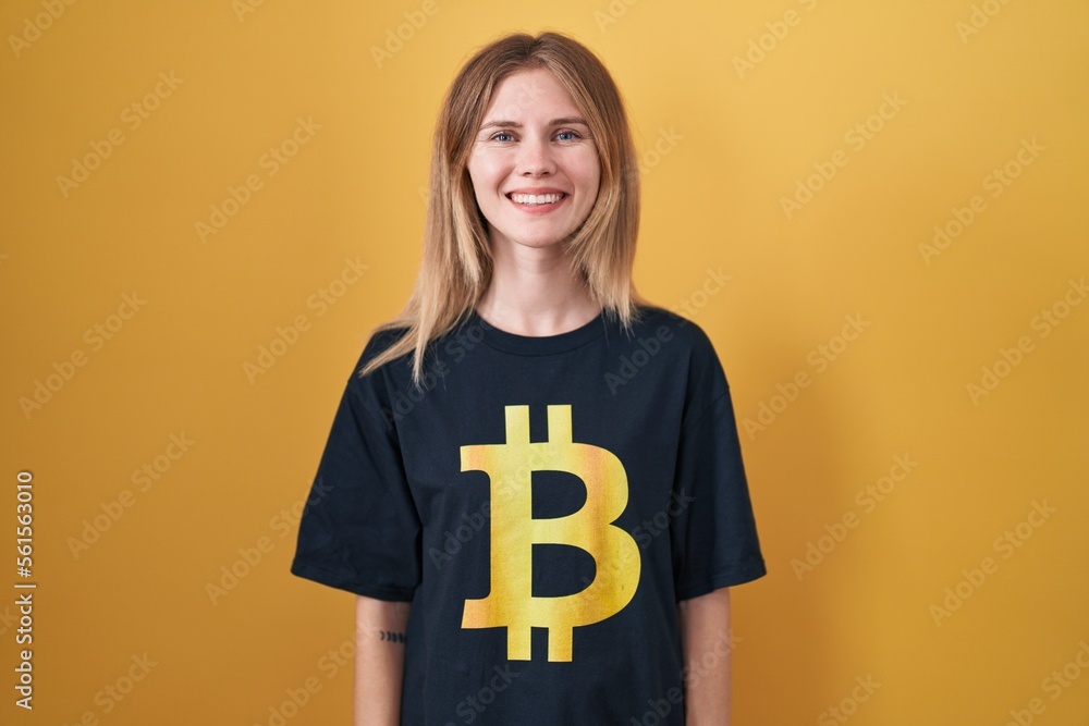Blonde caucasian woman wearing bitcoin t shirt with a happy and cool smile on face. lucky person. Blonde caucasian woman wearing bitcoin t shirt with a happy and cool smile on face. lucky person.