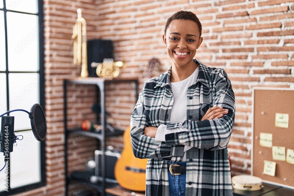 Fototapeta premium African american woman musician smiling confident standing with arms crossed gesture at music studio