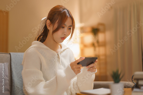 Nightlife concept, Young woman playing game on smartphone with excited in night time at winter