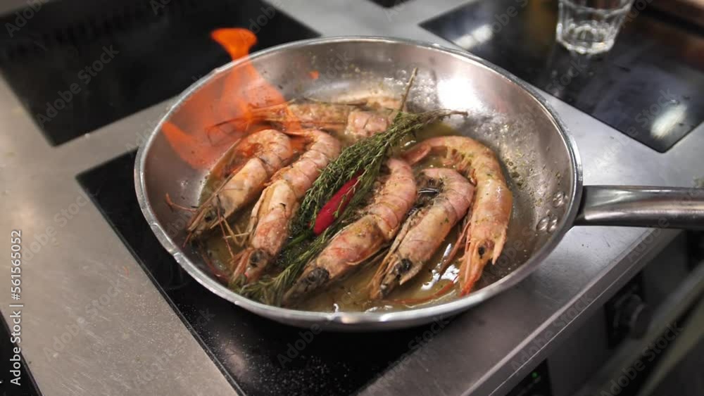 Large shrimp are cooked in a frying pan with a fire show. Open the oven when frying shrimp. Large shrimp are cooked in a frying pan with a fire show. Open the oven when frying shrimp.