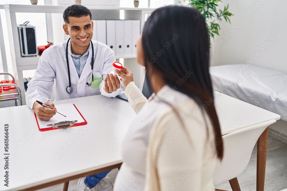 Fototapeta premium Young latin couple doctor and patient having medical session holding urine test tube at clinic