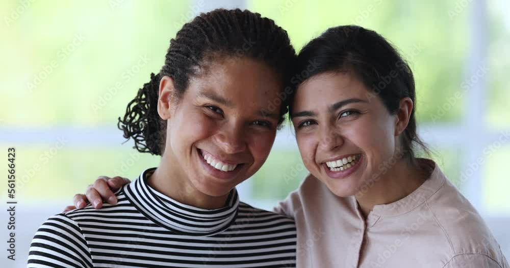 Close up head shot portrait of two multi ethnic beautiful female, Indian and African best girls friends hugging smile staring at camera feel happy. Strong friendship or multiracial women, amity, unity Close up head shot portrait of two multi ethnic beautiful female, Indian and African best girls friends hugging smile staring at camera feel happy. Strong friendship or multiracial women, amity, unity