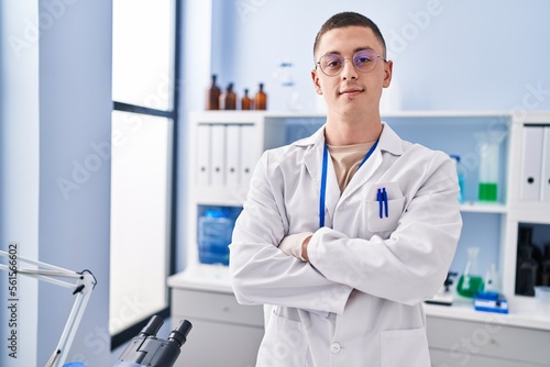 Young hispanic man scientist smiling confident standing with arms crossed gesture at laboratory