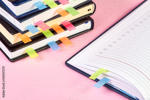 Close-up of an open notepad with colorful sticky page markers on background of a stack of office notepads