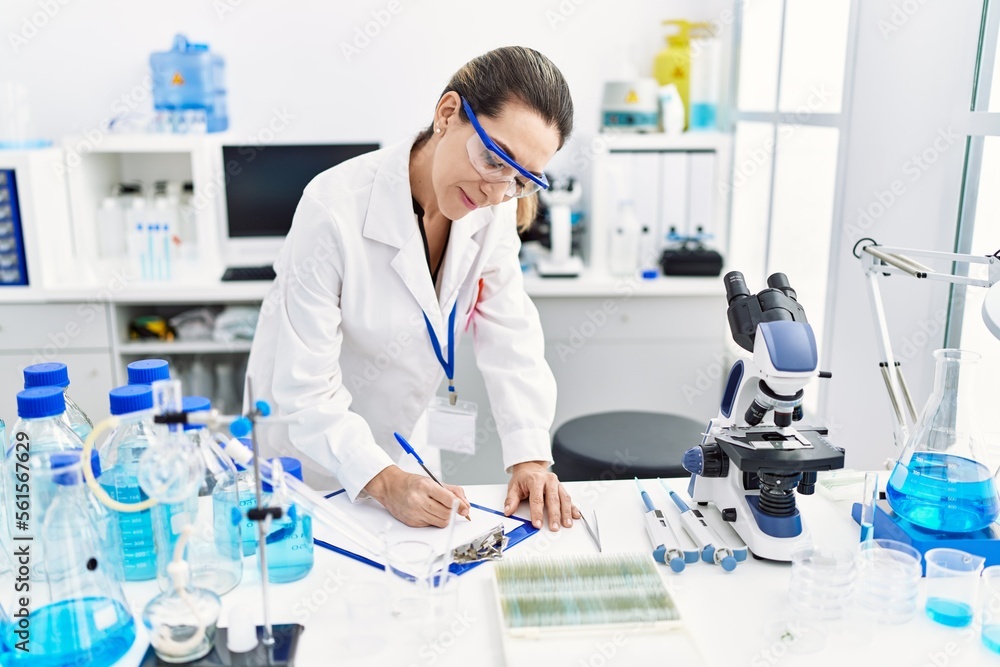 Young hispanic woman wearing scientist uniform holding test tube at laboratory Young hispanic woman wearing scientist uniform holding test tube at laboratory