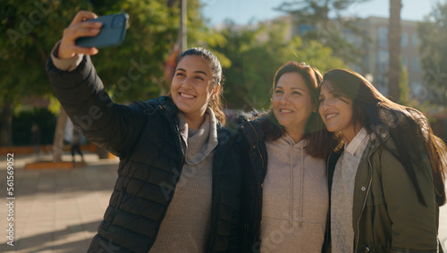 Mother and daugthers making selfie by the smartphone standing together at park