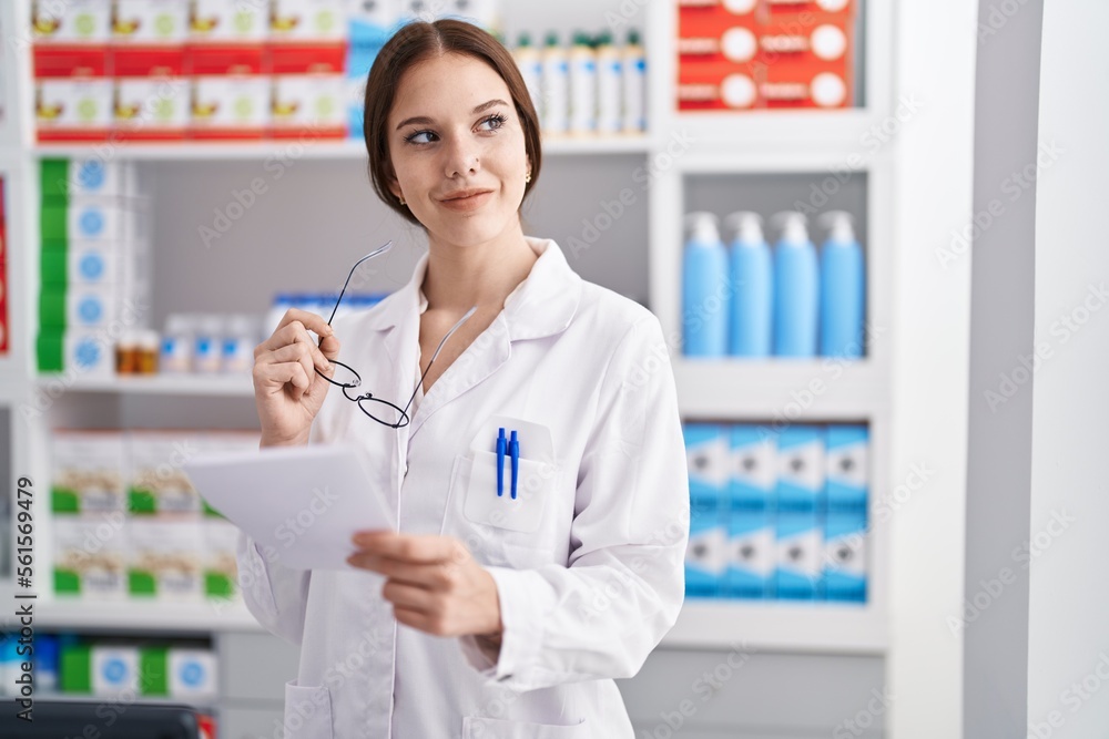 Young woman pharmacist reading prescription at pharmacy