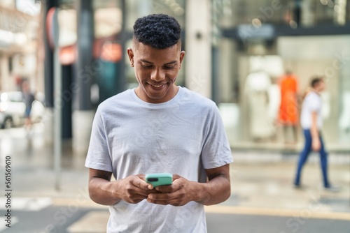 Young latin man smiling confident using smartphone at street © Krakenimages.com
