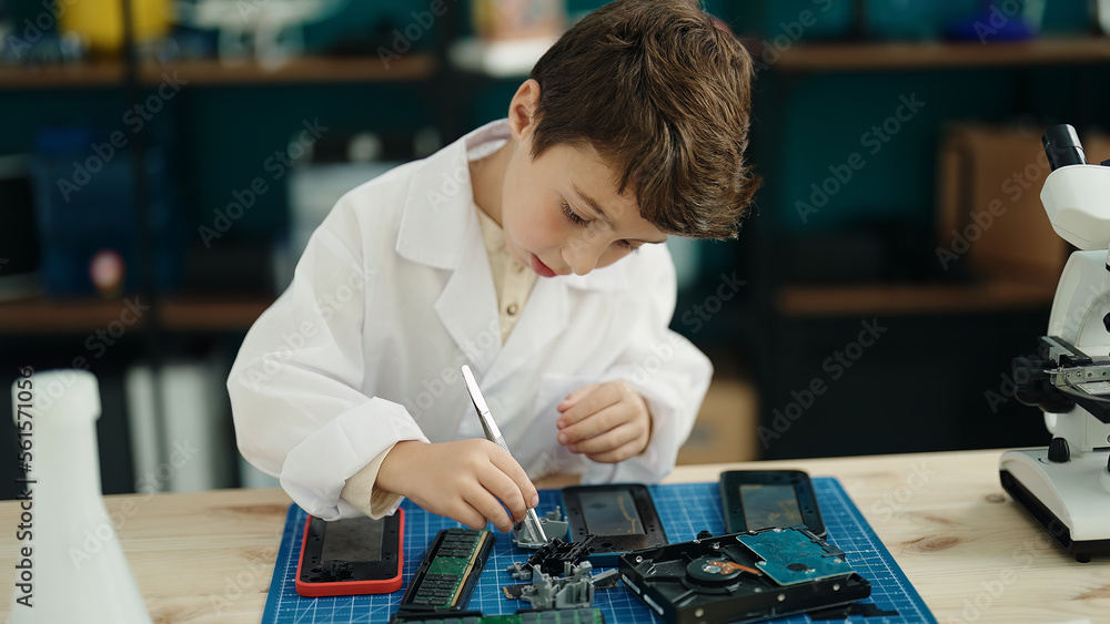 Fototapeta premium Adorable hispanic boy student repairing smartphone at laboratory classroom