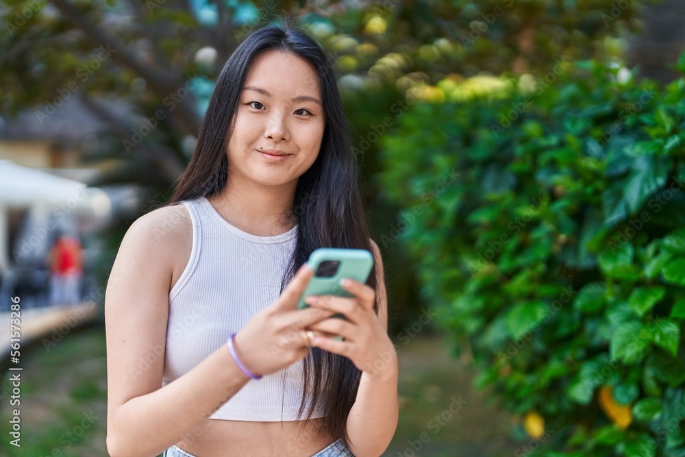 Young chinese woman smiling confident using smartphone at park