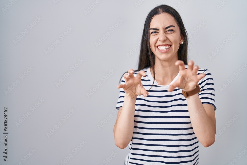 Young brunette woman wearing striped t shirt smiling funny doing claw gesture as cat, aggressive and sexy expression Young brunette woman wearing striped t shirt smiling funny doing claw gesture as cat, aggressive and sexy expression