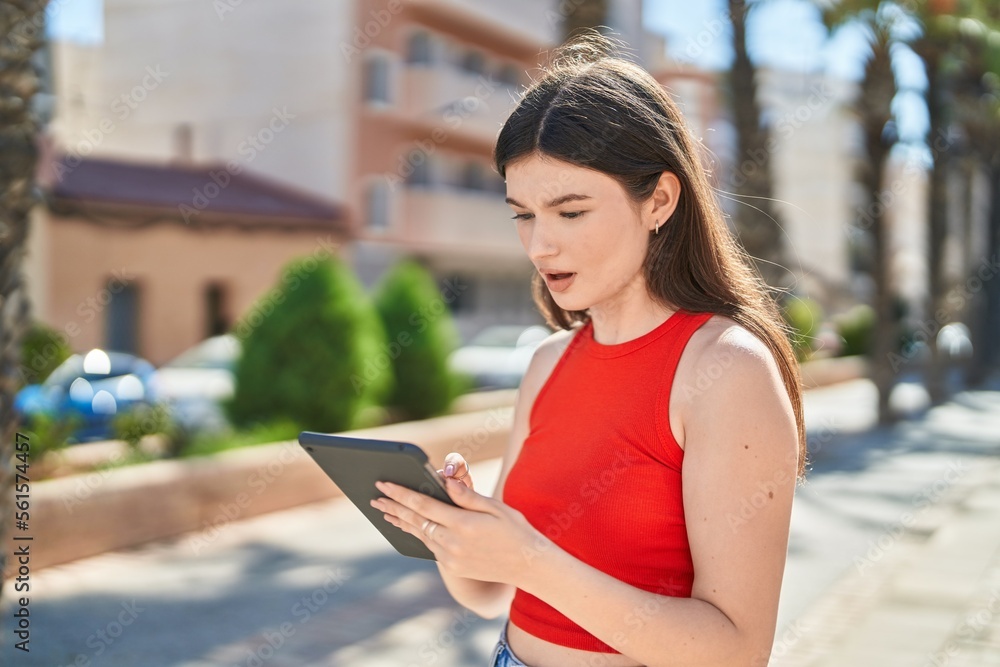 Fototapeta premium Young caucasian woman using touchpad with serious expression at park