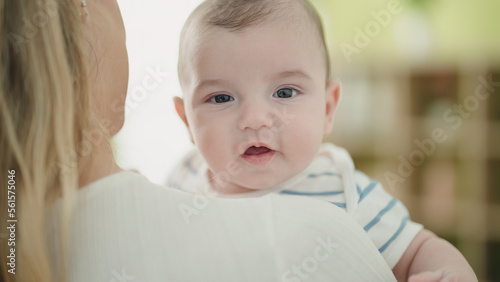 Adorable caucasian baby smiling confident on mother arms at home