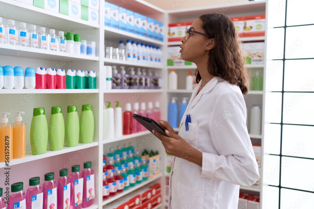Young african american woman pharmacist using touchpad working at pharmacy Young african american woman pharmacist using touchpad working at pharmacy