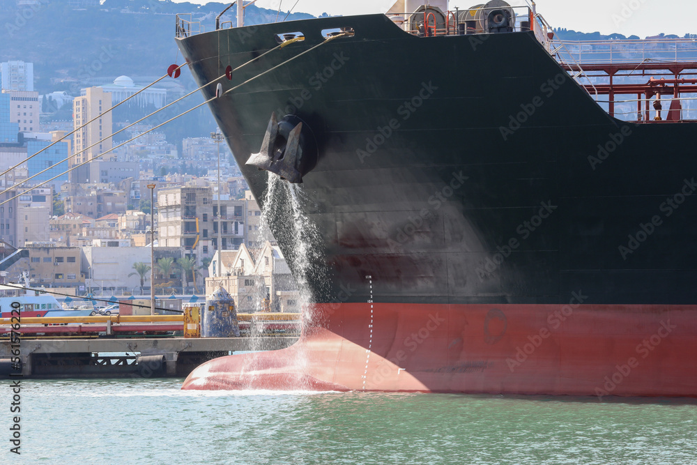Large anchored cargo ship discharging ballast water out from Anchor's ...