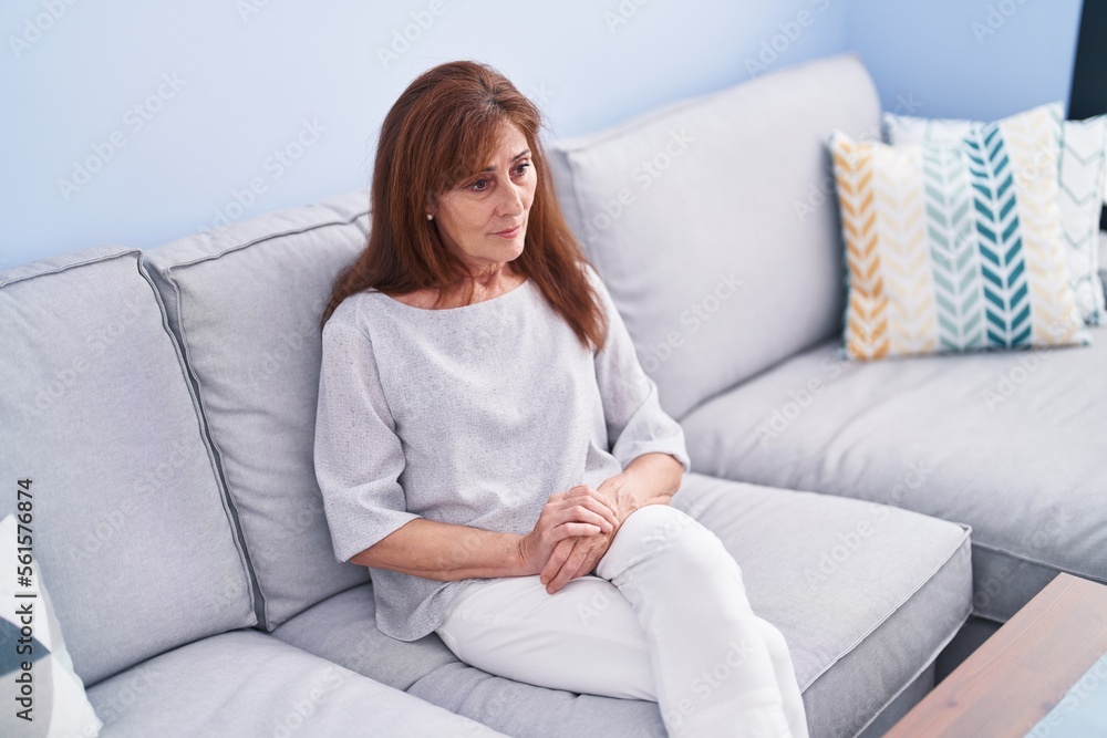 Middle age woman sitting on sofa with serious expression at home Middle age woman sitting on sofa with serious expression at home