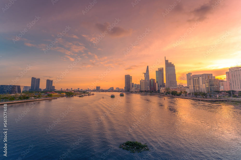 Aerial sunset view of Bitexco Tower, buildings, roads, Bason bridge and Saigon river in Ho Chi Minh city, container cargo ship on Saigon river. Travel concept.