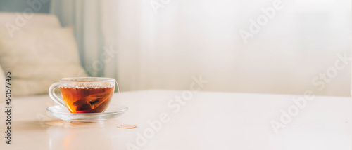 Foto Glass cup with black tea from a tea bag on the table, home tea drinking