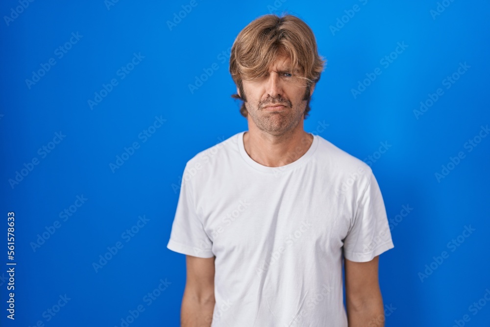 Middle age man standing over blue background skeptic and nervous, frowning upset because of problem. negative person. Middle age man standing over blue background skeptic and nervous, frowning upset because of problem. negative person.