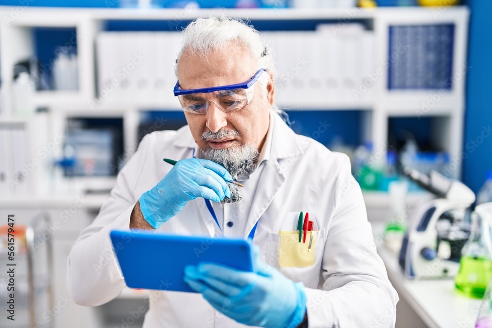 Middle age grey-haired man scientist using touchpad at laboratory Middle age grey-haired man scientist using touchpad at laboratory