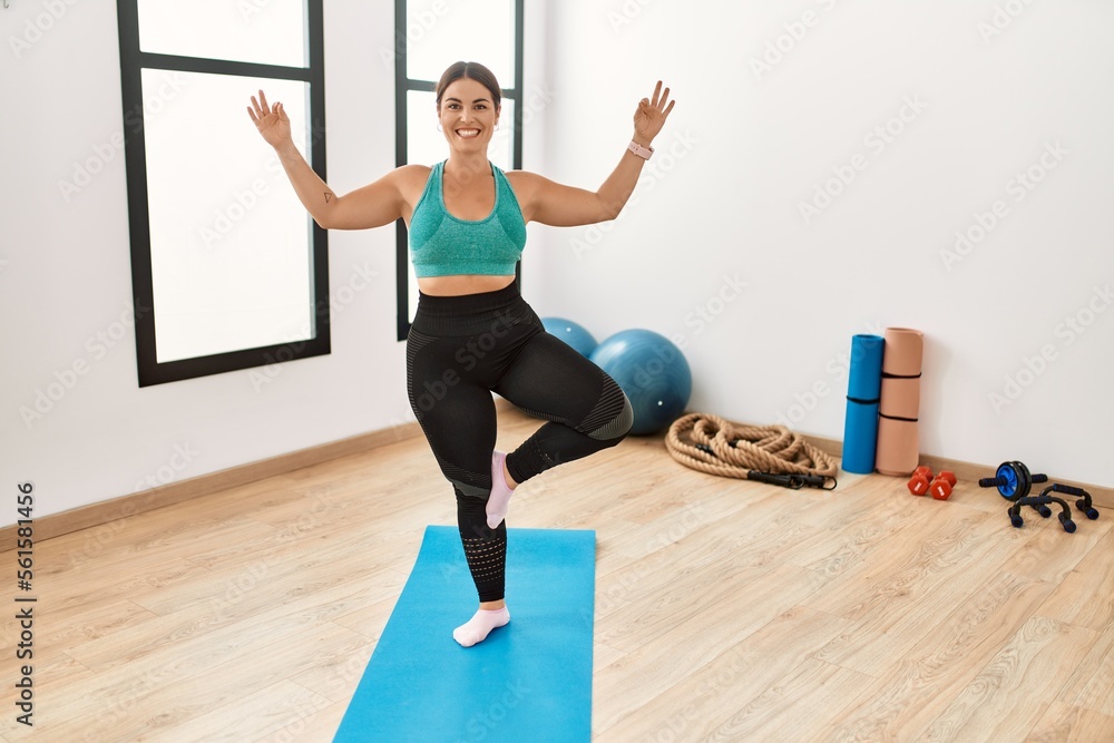 Fototapeta premium Young beautiful hispanic woman smiling confident training yoga at sport center