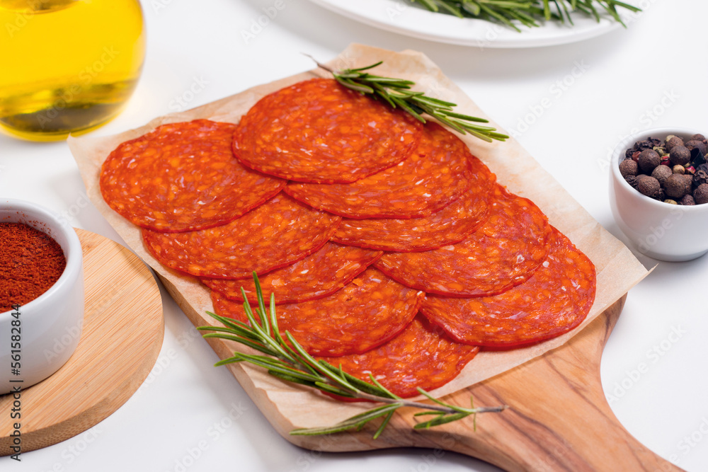Chorizo sausage and salami, thin cut. Spanish salami on the wood background with spices, paprika, rosemary and olives. Spicy food. Antipasto and appetizer meat. Chorizo sausage and salami, thin cut. Spanish salami on the wood background with spices, paprika, rosemary and olives. Spicy food. Antipasto and appetizer meat.