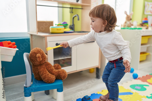 Adorable hispanic girl playing with play kitchen standing at home