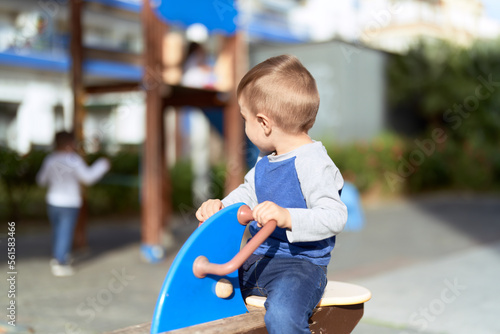 Adorable toddler playing on swing at park playground