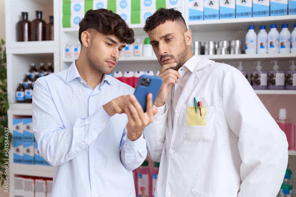 Two hispanic men client showing smartphone to pharmacist at pharmacy Two hispanic men client showing smartphone to pharmacist at pharmacy