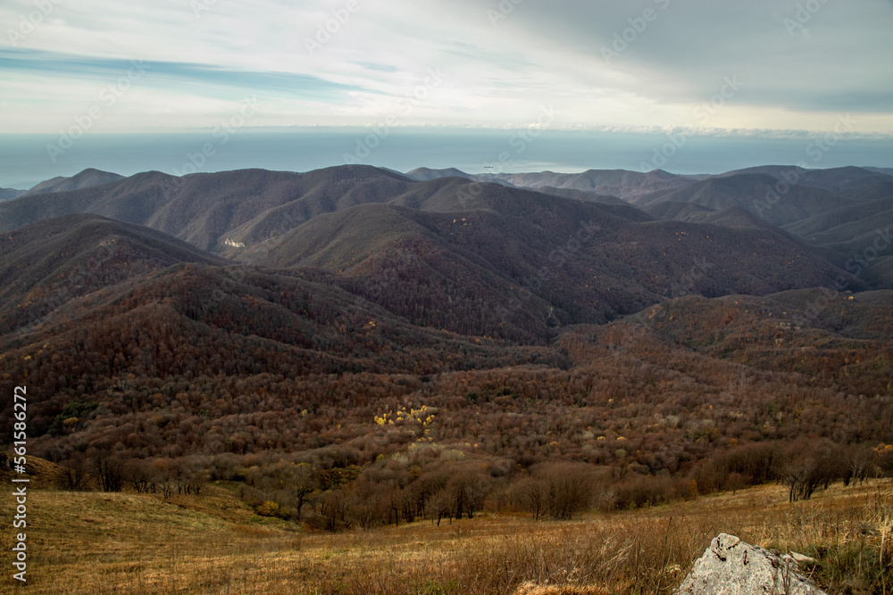 View from a height of 1000 m to the peaks of the North-Western Caucasus. Stunning view of the mountain landscape under a cloudy sky. Stunning view from the rocky peak of Mount Peus on a sunny day.