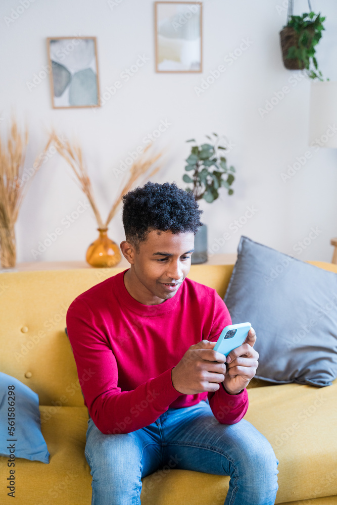 Black man using smartphone on sofa