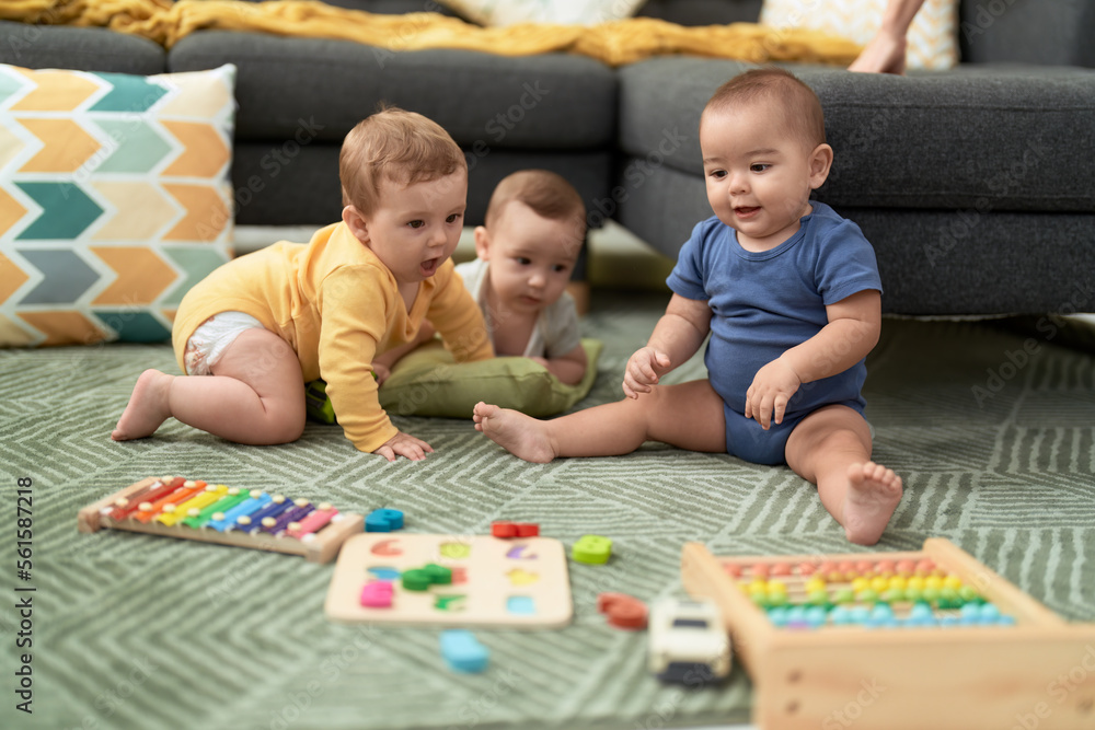 Fototapeta premium Group of toddlers playing with toys sitting on floor at home