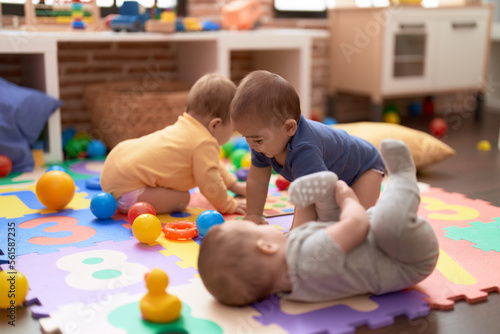 Photos Group of toddlers playing with toys crawling on floor at kindergarten