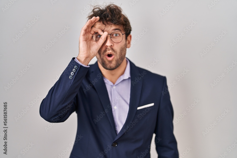 Hispanic business man wearing glasses doing ok gesture shocked with surprised face, eye looking through fingers. unbelieving expression. Hispanic business man wearing glasses doing ok gesture shocked with surprised face, eye looking through fingers. unbelieving expression.