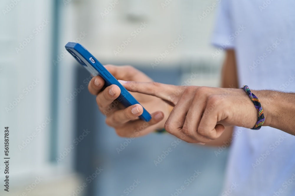 Young hispanic man using smartphone at street