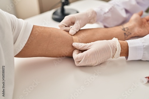 Man and woman wearing doctor uniform having blood analysis at clinic