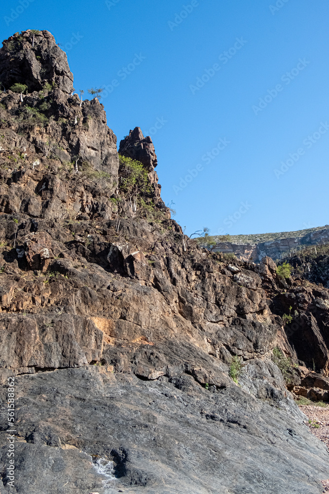 Naklejka premium Sunlit cliff with view and brown rocks