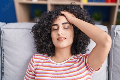 Young middle eastern woman relaxed with hand on head sitting on sofa at home © Krakenimages.com