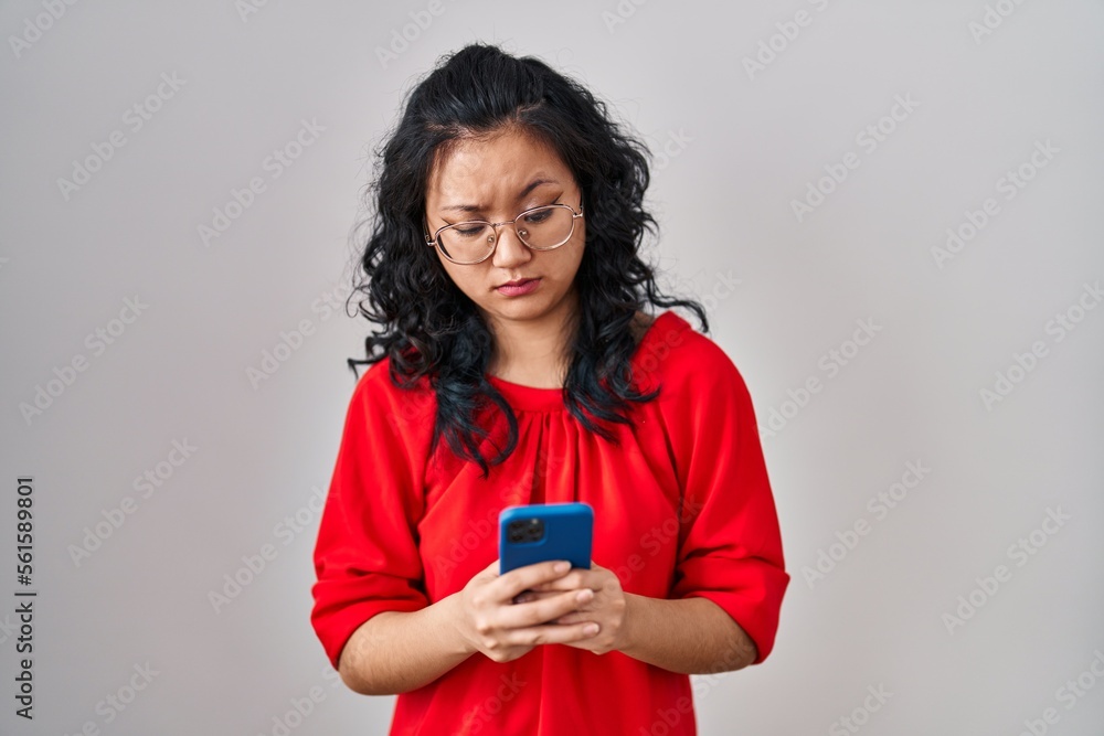 Young asian woman using smartphone typing message skeptic and nervous, frowning upset because of problem. negative person. Young asian woman using smartphone typing message skeptic and nervous, frowning upset because of problem. negative person.