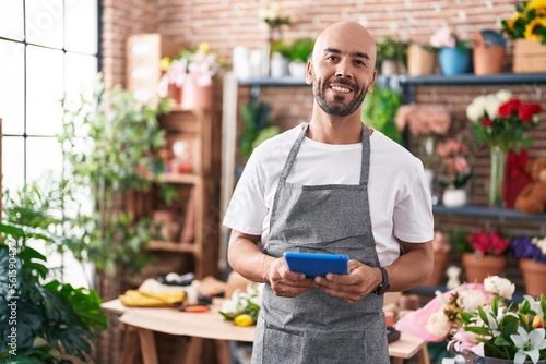 Young bald man florist smiling confident using touchpad at florist