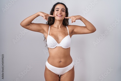 Young hispanic woman wearing white lingerie smiling cheerful showing and pointing with fingers teeth and mouth. dental health concept. © Krakenimages.com