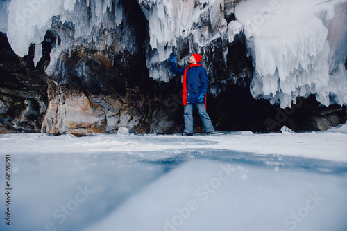 Tourist man with red scarf background ice grotto and cave lake Baikal. Adventure winter travel photo