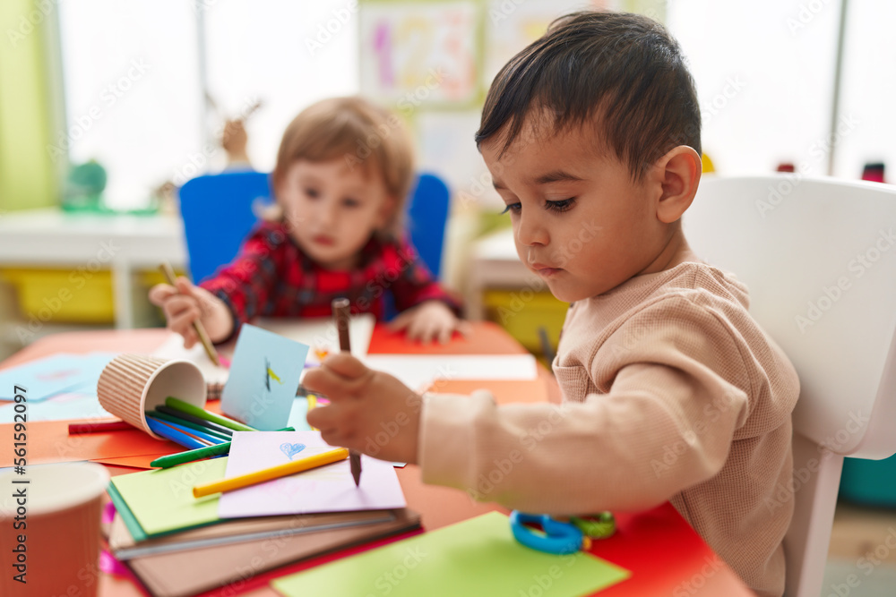 Two kids preschool students sitting on table drawing on paper at kindergarten Two kids preschool students sitting on table drawing on paper at kindergarten