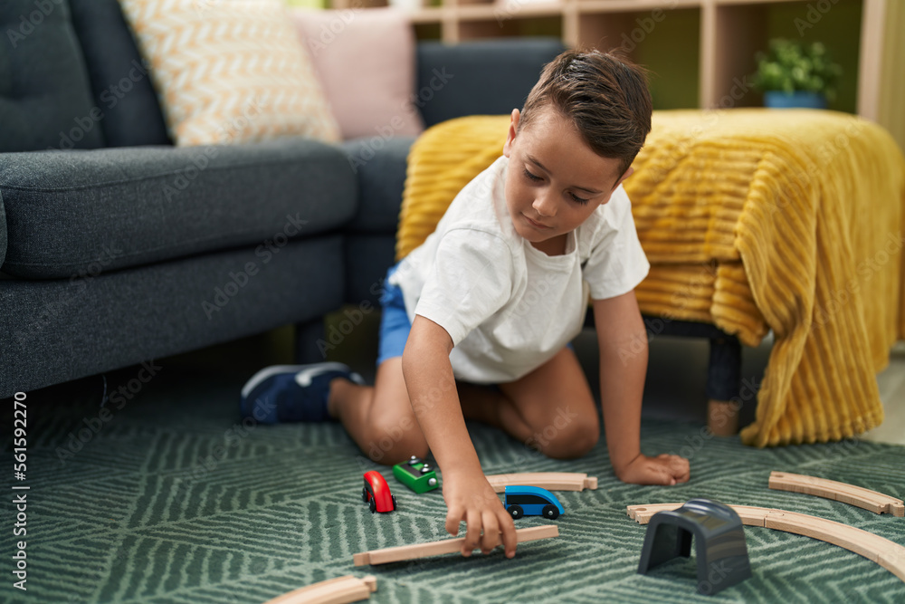 Adorable hispanic toddler playing with car game sitting on floor at home