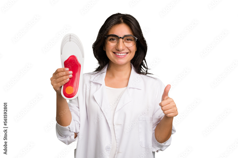 Young indian chiropodist woman holding a insoles for shoes cut out isolated smiling and raising thumb up Young indian chiropodist woman holding a insoles for shoes cut out isolated smiling and raising thumb up