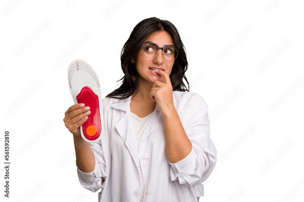 Young indian chiropodist woman holding a insoles for shoes cut out isolated relaxed thinking about something looking at a copy space. Young indian chiropodist woman holding a insoles for shoes cut out isolated relaxed thinking about something looking at a copy space.