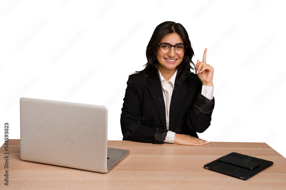 Young indian woman in a table with a laptop and tablet isolated showing number one with finger. Young indian woman in a table with a laptop and tablet isolated showing number one with finger.