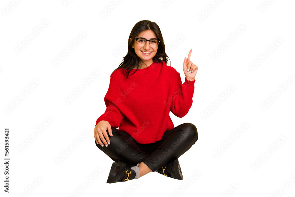 Young indian woman sitting on the floor cut out isolated showing number one with finger. Young indian woman sitting on the floor cut out isolated showing number one with finger.