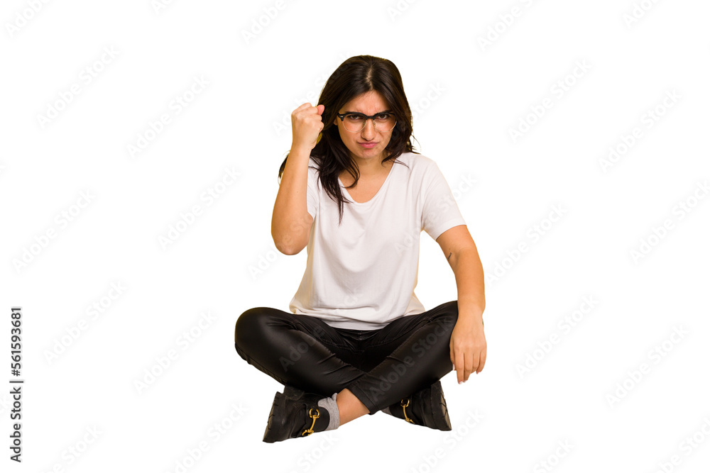 Young indian woman sitting on the floor cut out isolated showing fist to camera, aggressive facial expression. Young indian woman sitting on the floor cut out isolated showing fist to camera, aggressive facial expression.