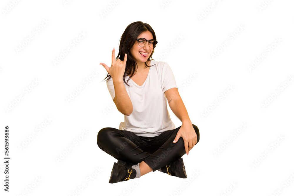 Young indian woman sitting on the floor cut out isolated showing rock gesture with fingers Young indian woman sitting on the floor cut out isolated showing rock gesture with fingers